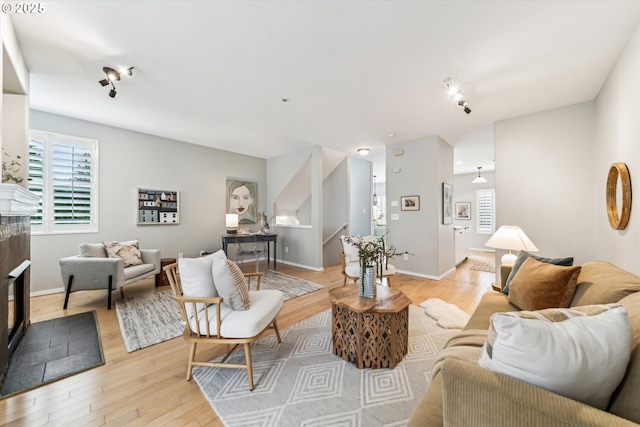 living room with light wood-type flooring, baseboards, and a tile fireplace