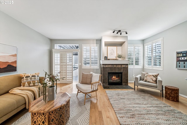 living room with rail lighting, baseboards, a tiled fireplace, and wood finished floors