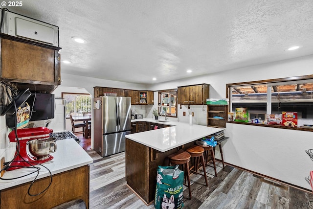 1366 Lakeshore Dr, Coos Bay, OR 97420 - kitchen with freestanding refrigerator, a textured ceiling, a peninsula, light countertops, and wood finished floors