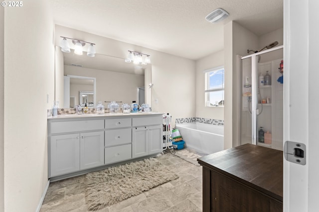 bathroom featuring a textured ceiling, plus walk in shower, and vanity