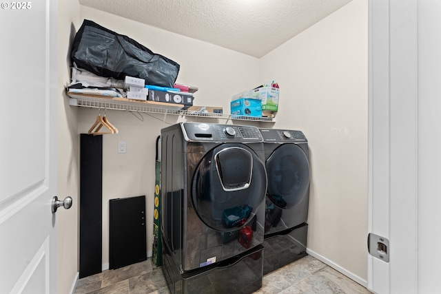 laundry area featuring a textured ceiling and washer and clothes dryer