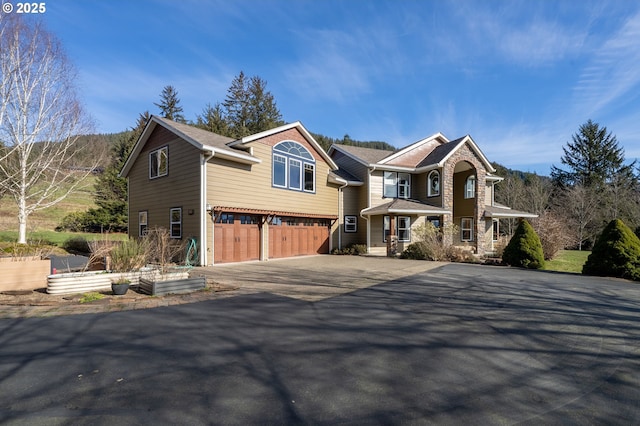 view of front of house with stone siding, an attached garage, and driveway