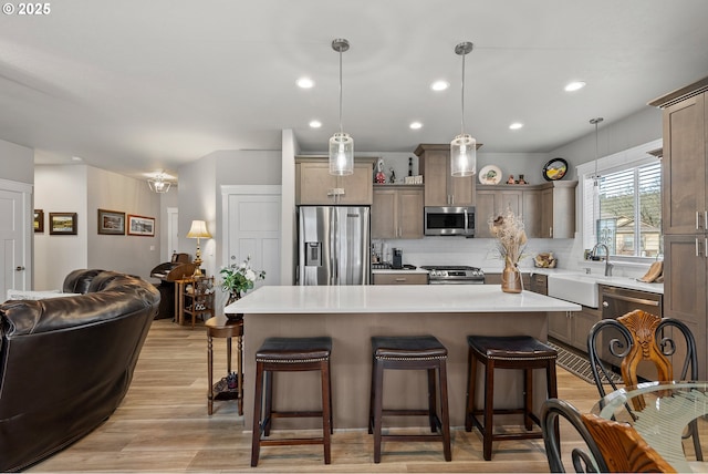 kitchen featuring a kitchen breakfast bar, hanging light fixtures, appliances with stainless steel finishes, backsplash, and a center island