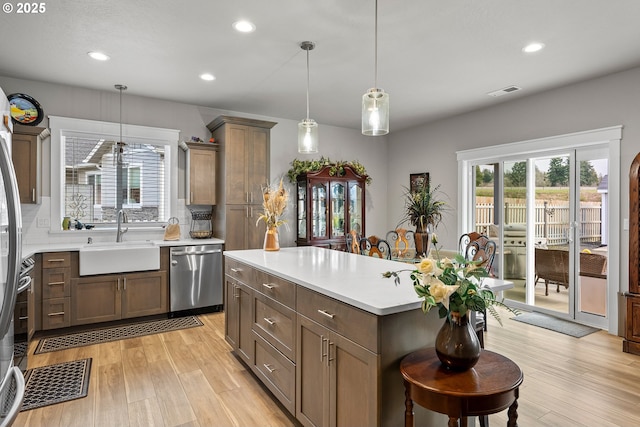 kitchen featuring stainless steel dishwasher, sink, decorative light fixtures, a center island, and decorative backsplash