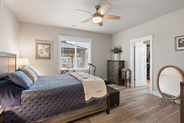 bedroom featuring ceiling fan, light hardwood / wood-style floors, a closet, and a walk in closet