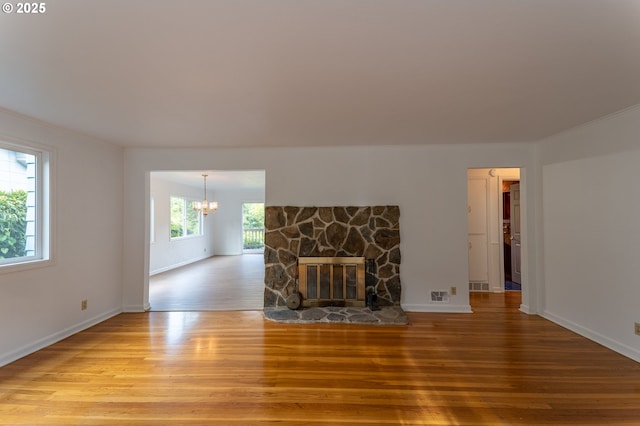 725 N 9th St, Coos Bay, OR 97420 - unfurnished living room featuring wood finished floors, a chandelier, crown molding, a stone fireplace, and baseboards