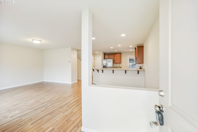 interior space featuring baseboards, stainless steel appliances, recessed lighting, light wood-type flooring, and brown cabinetry