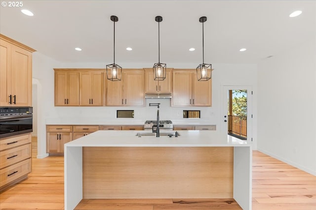1081 SE Balsamroot Ln, Madras, OR 97741 - kitchen featuring oven, light brown cabinets, light wood-style flooring, recessed lighting, and a kitchen island with sink