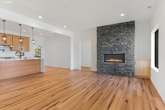 1081 SE Balsamroot Ln, Madras, OR 97741 - unfurnished living room with light wood-type flooring, recessed lighting, and a stone fireplace