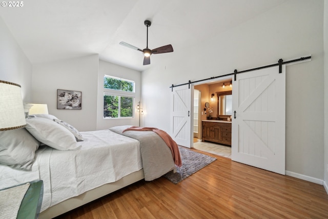 23295 SW Cascade Pl, Sherwood, OR 97140 - bedroom with a barn door, light wood-type flooring, lofted ceiling, baseboards, and ensuite bathroom