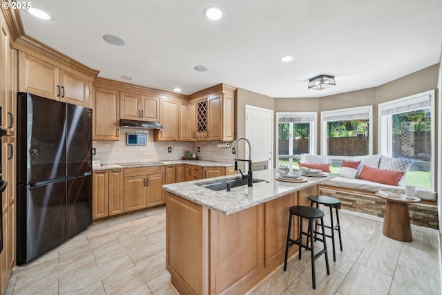 23295 SW Cascade Pl, Sherwood, OR 97140 - kitchen with black appliances, a sink, tasteful backsplash, light stone countertops, and a kitchen breakfast bar