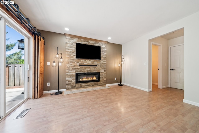 23295 SW Cascade Pl, Sherwood, OR 97140 - unfurnished living room with wood finished floors, a stone fireplace, baseboards, and recessed lighting