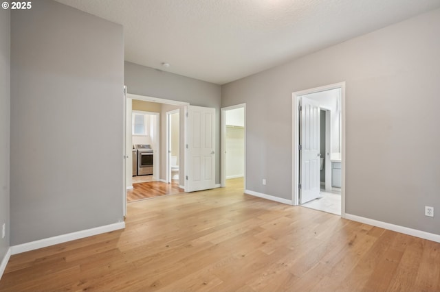 unfurnished room featuring light wood-type flooring, a textured ceiling, and baseboards