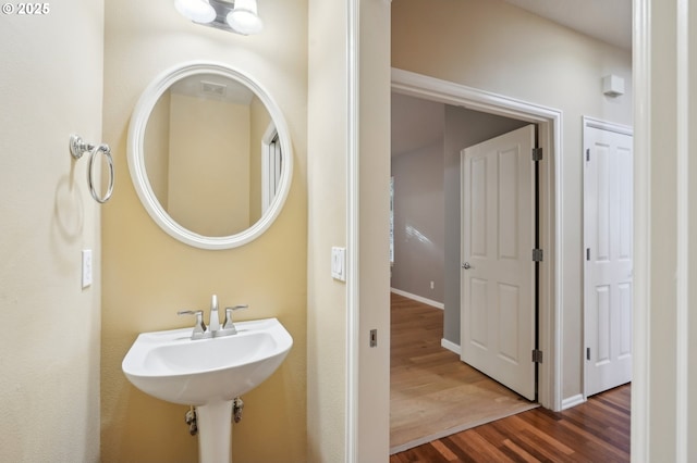 bathroom with visible vents, a sink, baseboards, and wood finished floors