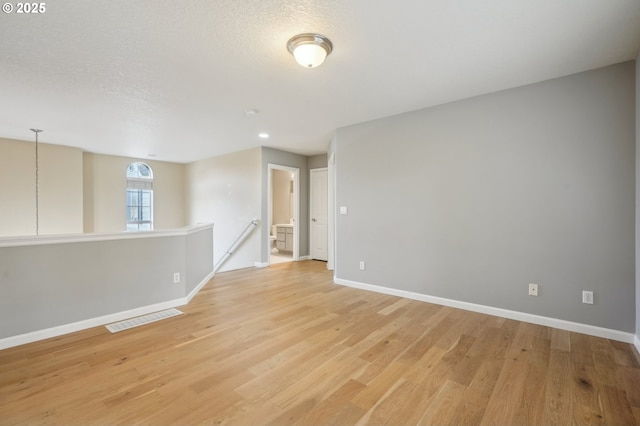 unfurnished room featuring a textured ceiling and light hardwood / wood-style flooring