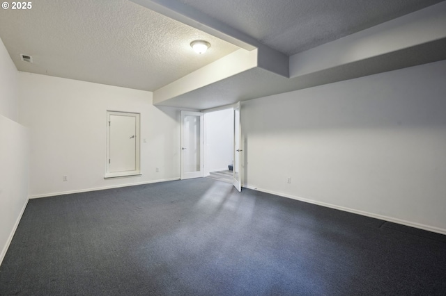 finished below grade area featuring baseboards, visible vents, and a textured ceiling