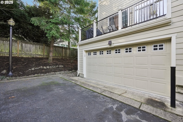 garage featuring aphalt driveway and fence