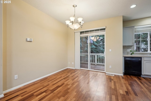 unfurnished dining area with recessed lighting, a notable chandelier, baseboards, and wood finished floors