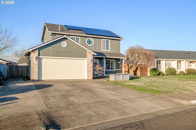 view of front of home featuring a garage, a porch, a front yard, and solar panels