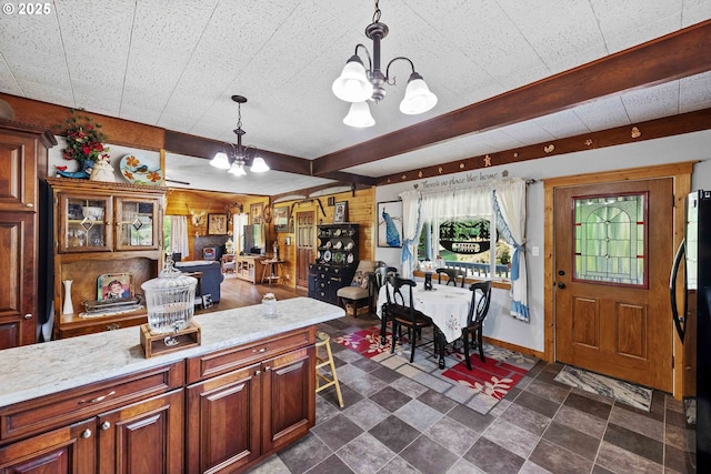 96863 Sitkum Ln, Myrtle Point, OR 97458 - kitchen featuring a chandelier, hanging light fixtures, freestanding refrigerator, light stone counters, and dark stone finish floors