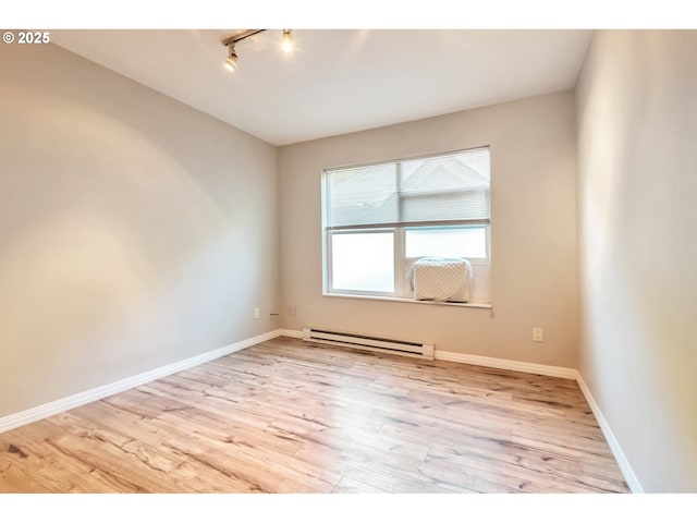 empty room with light wood-type flooring, rail lighting, baseboards, and baseboard heating
