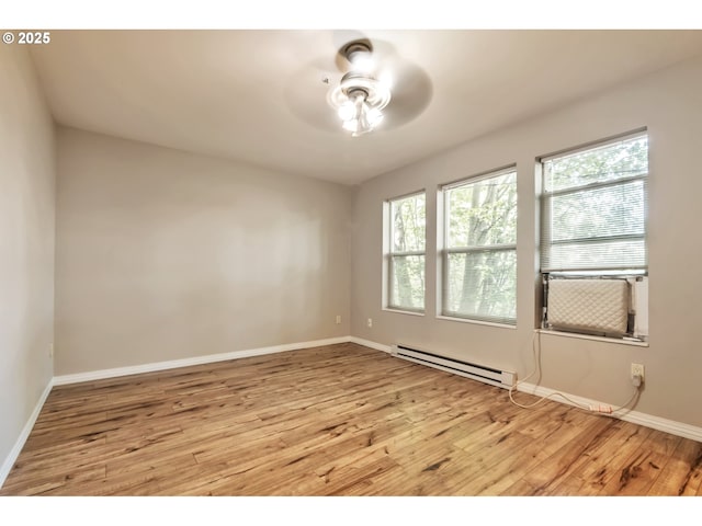 spare room with baseboards, ceiling fan, a baseboard heating unit, and light wood-style flooring