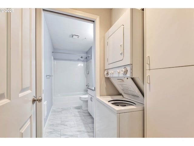 laundry area featuring visible vents, laundry area, stacked washer / dryer, and marble finish floor