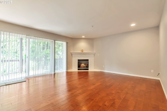 2709 SW 2nd Ave Unit 201, Portland, OR 97201 - unfurnished living room featuring a glass covered fireplace, baseboards, recessed lighting, and hardwood / wood-style floors