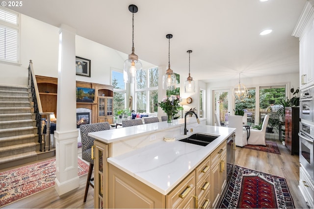 kitchen featuring light wood-type flooring, a wealth of natural light, a sink, and a glass covered fireplace