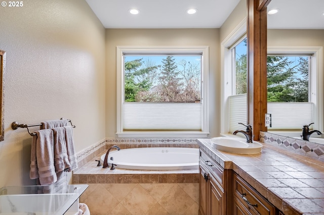 full bath with recessed lighting, a garden tub, plenty of natural light, and vanity