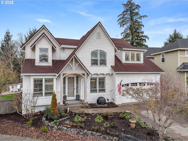 view of front of house featuring a garage, stone siding, a shingled roof, and fence