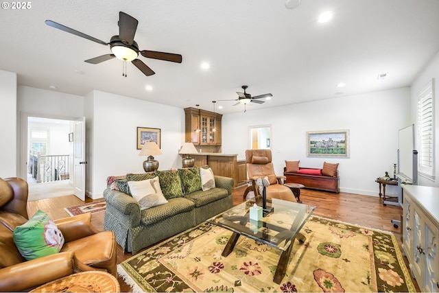 living room with recessed lighting, light wood-style flooring, and baseboards