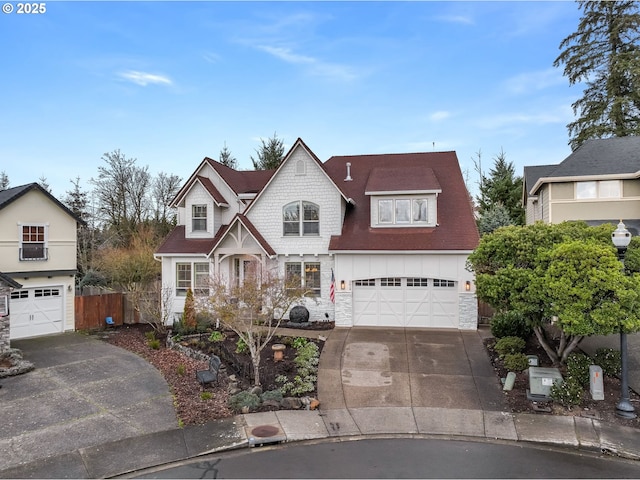 view of front of home with driveway, stone siding, a garage, and fence