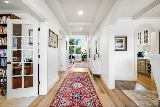 hall featuring arched walkways, ornamental molding, beamed ceiling, light wood-style floors, and recessed lighting