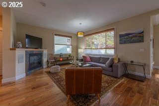 living room featuring wood finished floors, baseboards, and a glass covered fireplace