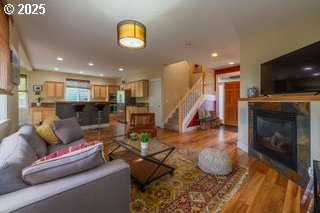 living room with a glass covered fireplace, wood finished floors, stairs, and recessed lighting