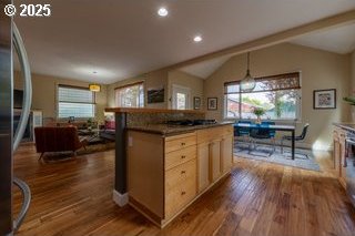 kitchen with healthy amount of natural light, dark wood finished floors, vaulted ceiling, light brown cabinets, and recessed lighting