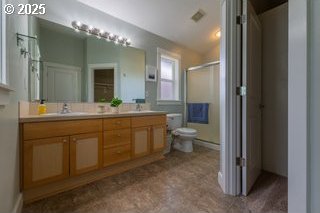 full bath featuring a shower stall, toilet, and double vanity
