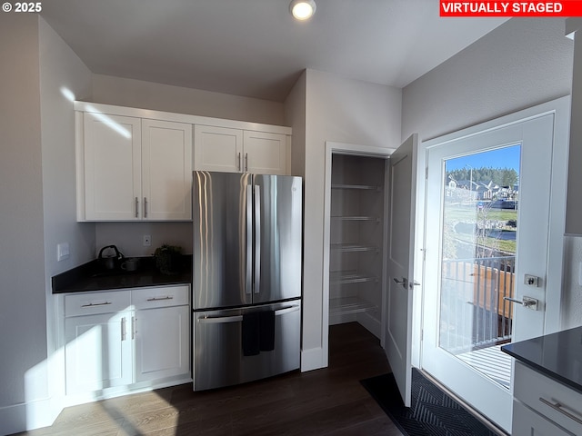 kitchen with dark countertops, white cabinetry, dark wood-style flooring, and freestanding refrigerator