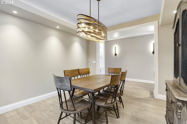 dining space with light wood-type flooring and a notable chandelier