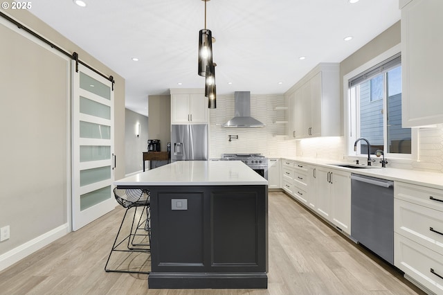 kitchen with a kitchen island, white cabinetry, wall chimney range hood, stainless steel appliances, and sink