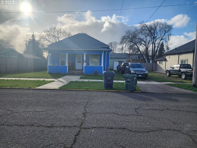 bungalow-style home with fence and a front lawn