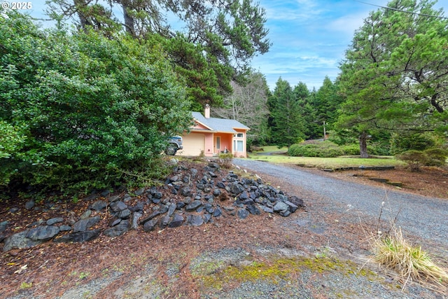 view of side of home with driveway and a chimney