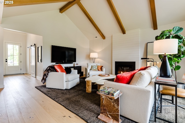 living area featuring wood-type flooring, beam ceiling, high vaulted ceiling, and a fireplace