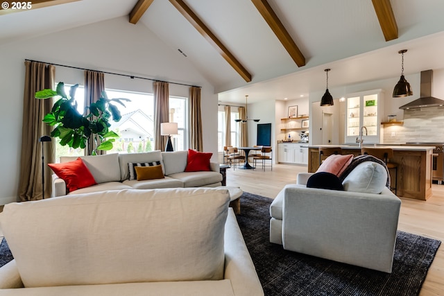 living room featuring light wood-style flooring, plenty of natural light, beam ceiling, and high vaulted ceiling
