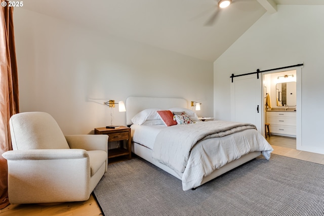 bedroom with wood finished floors, high vaulted ceiling, a barn door, beamed ceiling, and ensuite bath