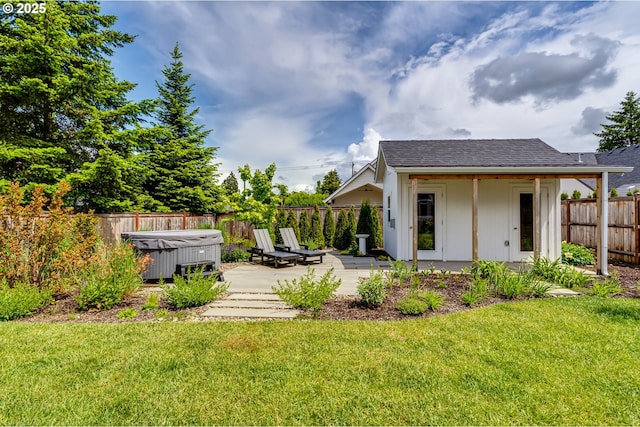 back of house featuring a hot tub, an outbuilding, a shingled roof, and a patio area
