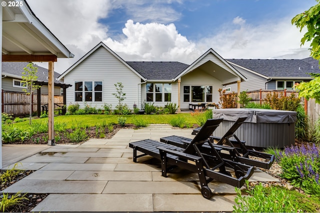 rear view of house with a hot tub and a patio area