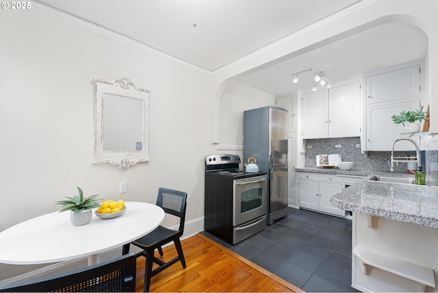 kitchen with dark wood-style flooring, decorative backsplash, appliances with stainless steel finishes, white cabinetry, and a sink