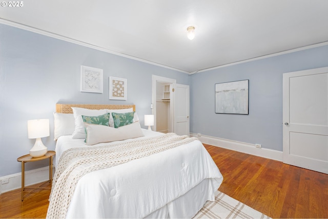 bedroom featuring ornamental molding, wood finished floors, and baseboards